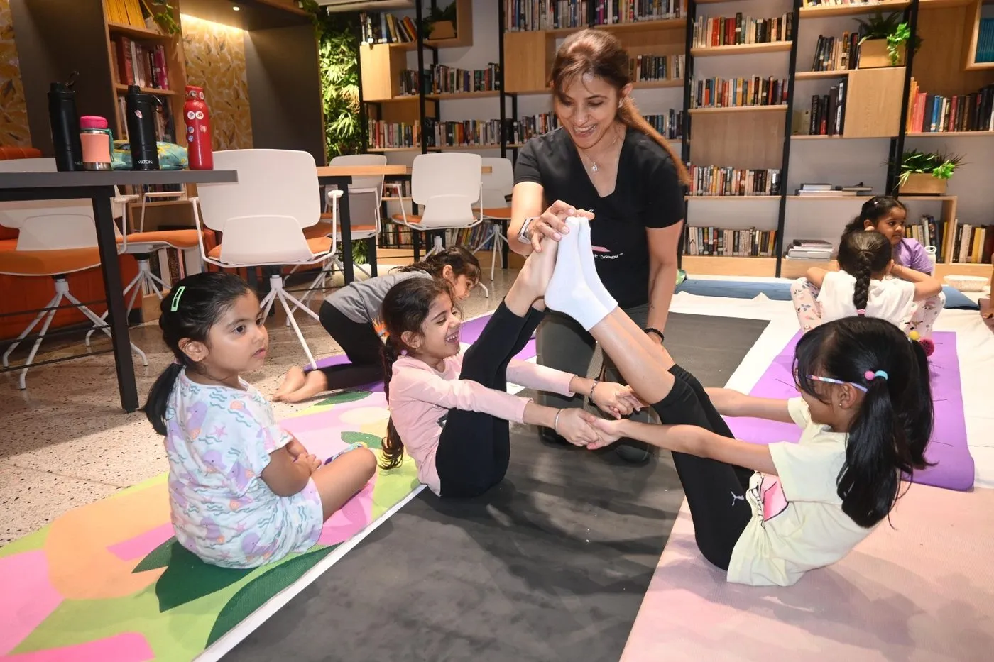A kids class in a bookshop, children stretching on mats in a circle