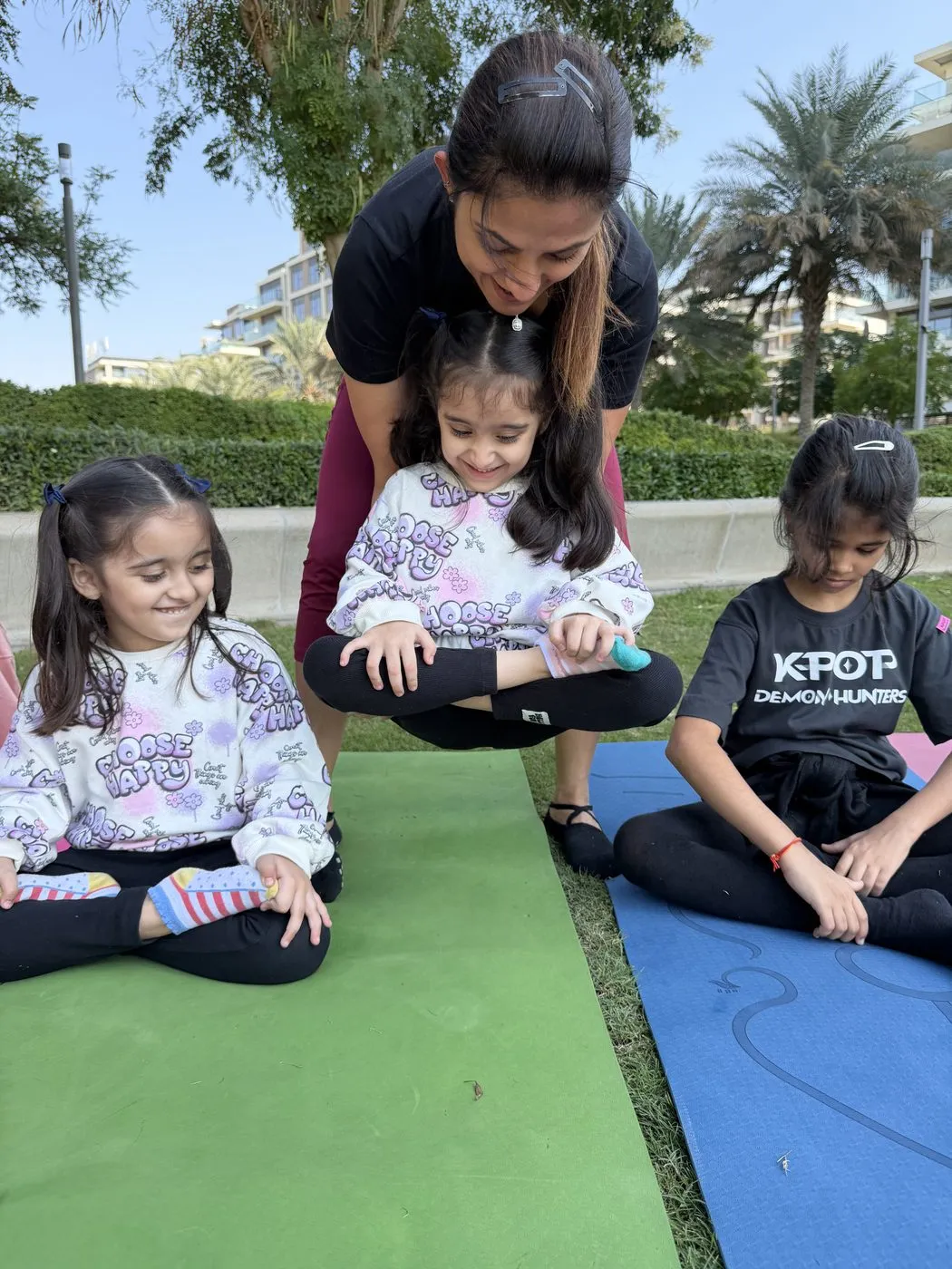 Brinda helping a toddler sit up on the mat while two older children practise